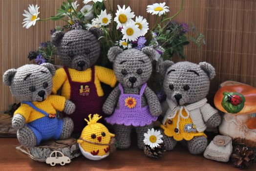 Charming knitted teddy bears surrounded by colorful flowers, perfect for still life décor.