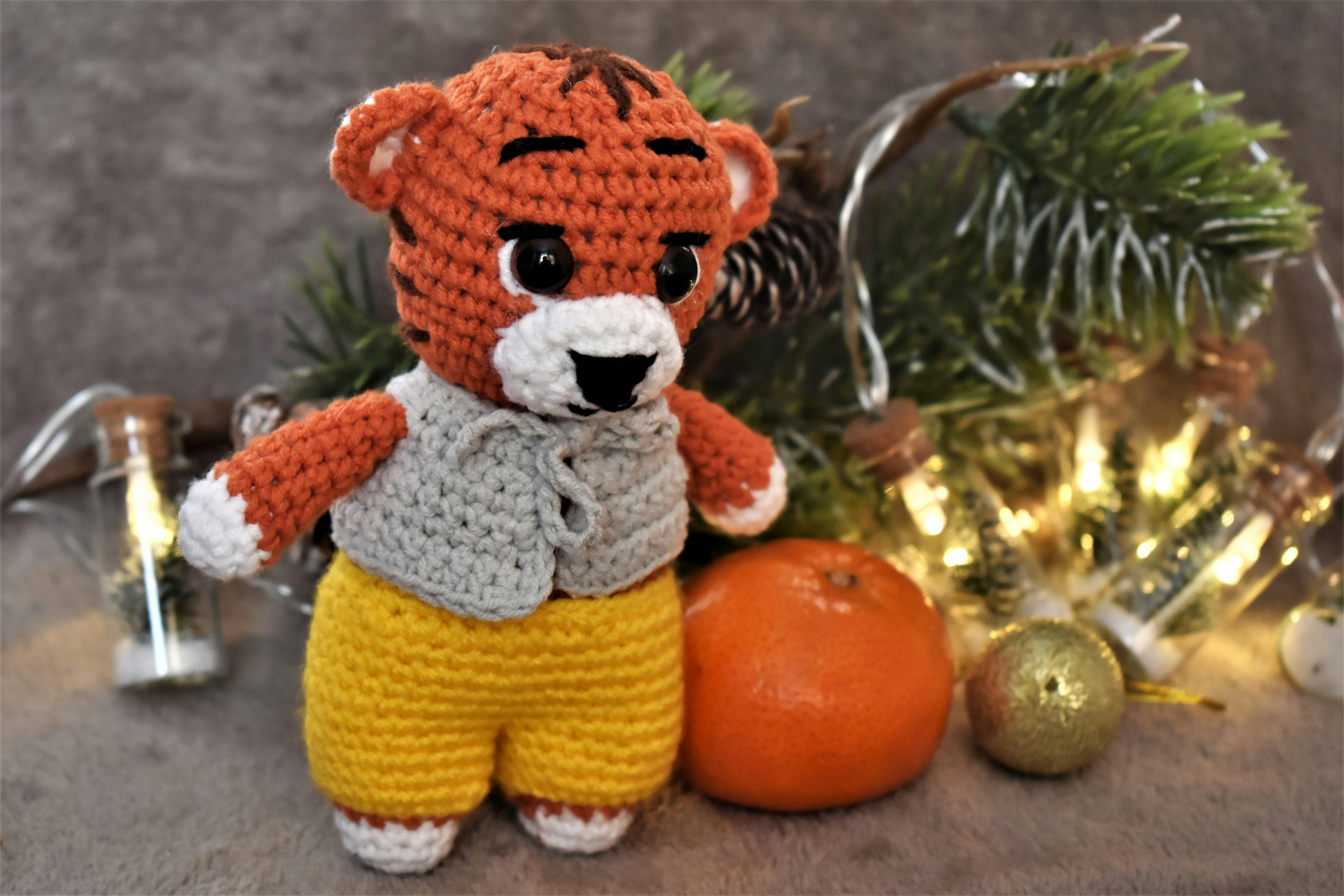 Cozy crochet tiger with festive decorations and lights, ideal for holiday crafts.