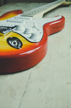 Detailed view of a colorful electric guitar placed on a wooden surface.