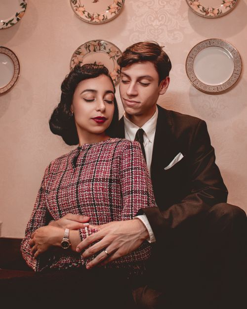 Free Vintage-style portrait of a couple in formal wear sitting indoors, capturing timeless elegance and affection. Stock Photo