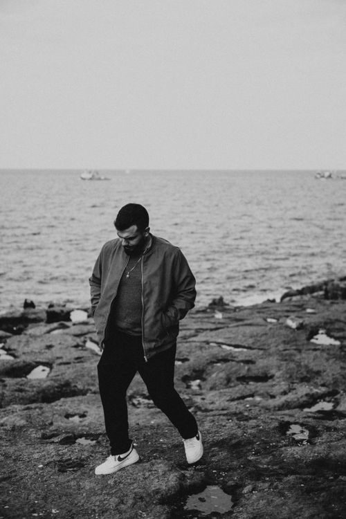 Free Man walking by the sea in black and white, capturing leisure and solitude. Stock Photo