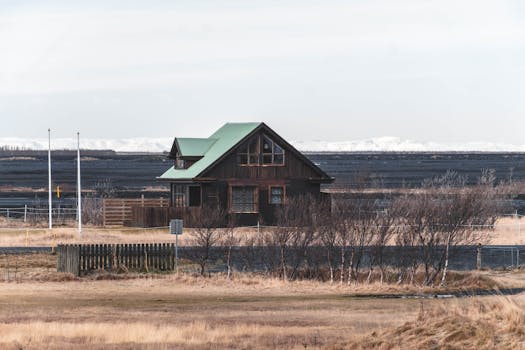 Charming wooden farmhouse set in the serene Icelandic landscape with distant snowy hills.