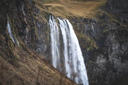 Stunning waterfall in Iceland cascades over rocky cliffs, captured in an autumn landscape.