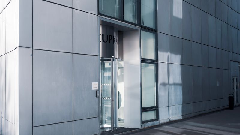 Sleek modern architecture featuring a glass entrance with reflective facade, showcasing contemporary design.