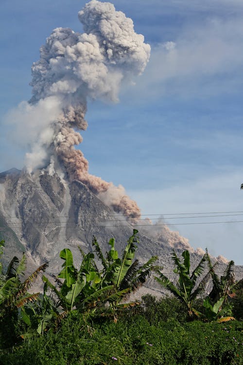 Erupting Volcano Under Blue Sunny Cloudy Sky