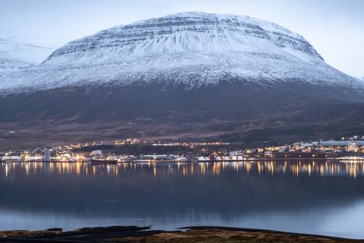 Peaceful fjord landscape in Eastern Iceland with snow-capped mountains and reflections.
