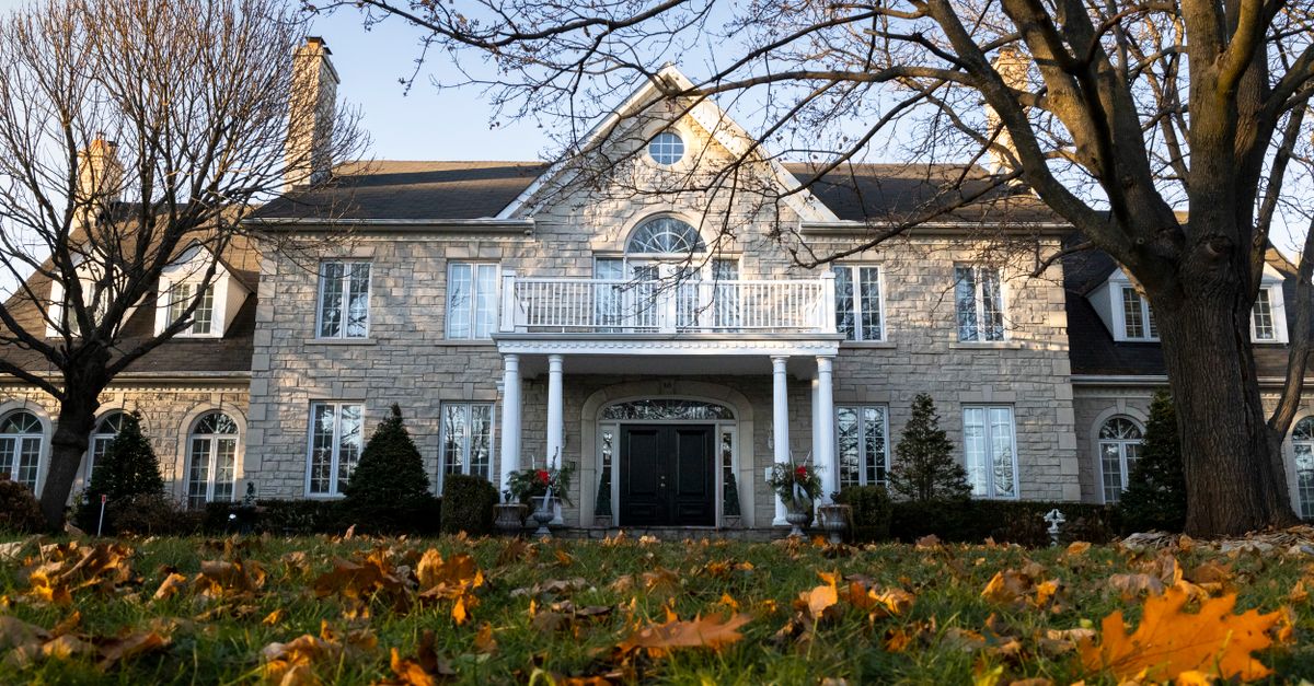 Charming stone house framed by bare trees and autumn leaves.