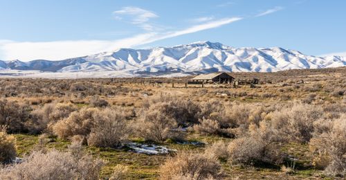 Free A scenic view of snow-covered mountains with a rustic barn in the foreground, capturing serene rural beauty. Stock Photo