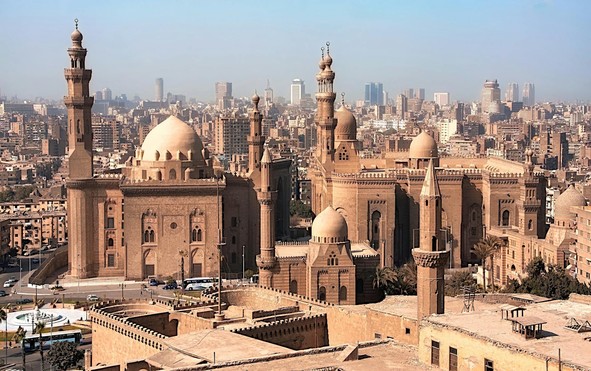 Aerial view of historic mosques with Cairo cityscape backdrop, showcasing Islamic architecture.