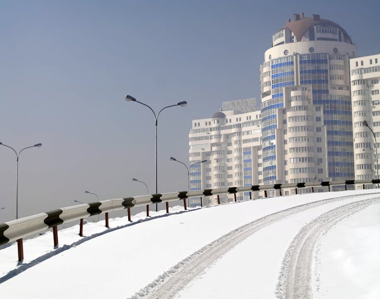 Snow On Road With Building In Background