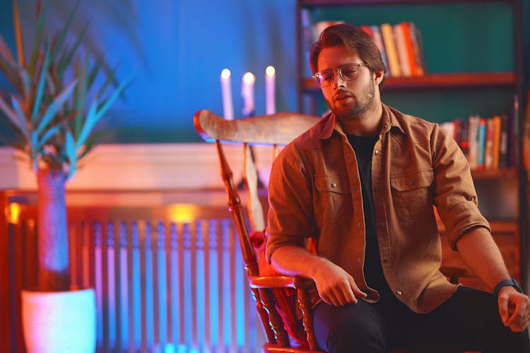 Man In Eyeglasses And Jacket Sitting On Armchair