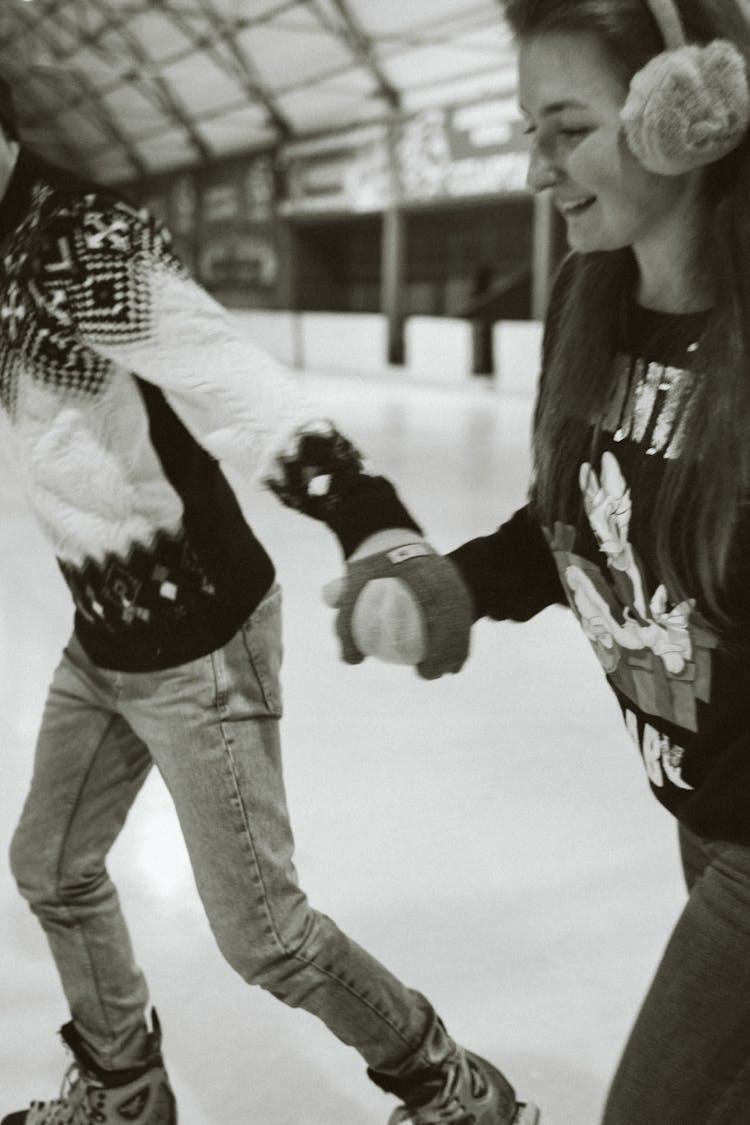 Couple Holding Hands And Skating On An Ice Skating Rink