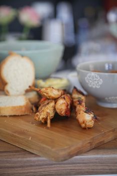 Delicious grilled chicken skewers served with bread and soup on a rustic wooden board, perfect for meals.