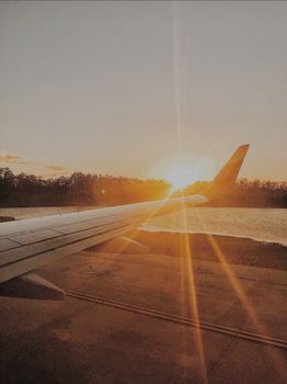 View of an airplane wing with a stunning sunset on the horizon, creating a warm and serene atmosphere.