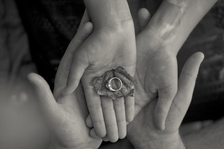 Person Holding Leaf And Ring In Grayscale