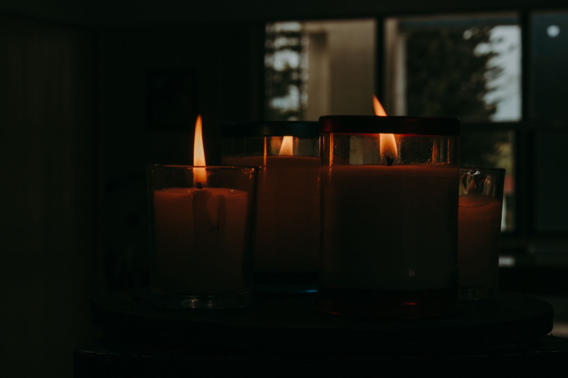 Peaceful arrangement of lit candles casting a warm glow in a dim room, perfect for meditation or relaxation imagery.