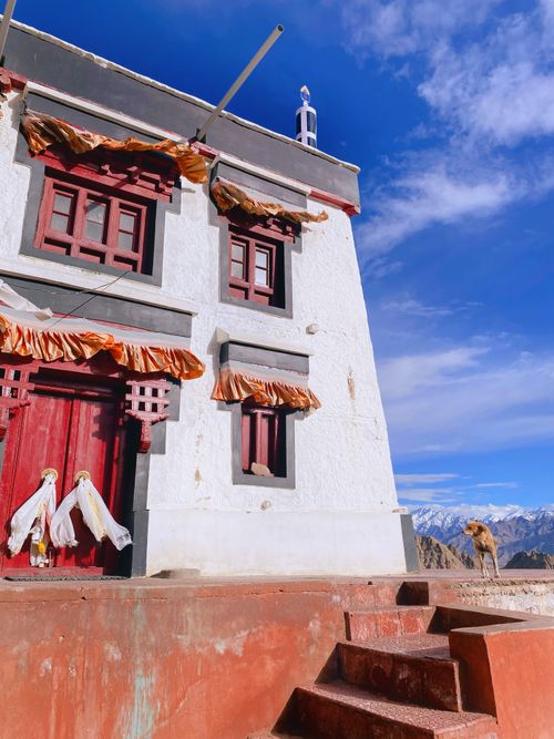 Free Traditional Himalayan building under a clear blue sky with mountains in the background. Stock Photo