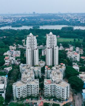 A drone captures a scenic cityscape featuring high-rise buildings surrounded by lush greenery.
