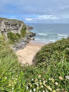 Explore this idyllic cliffside beach in Cantabria, Spain, offering stunning ocean views and natural beauty.