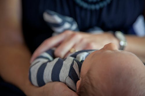 Female in Blue Top Holding Baby in Blue and Gray Stripe Top