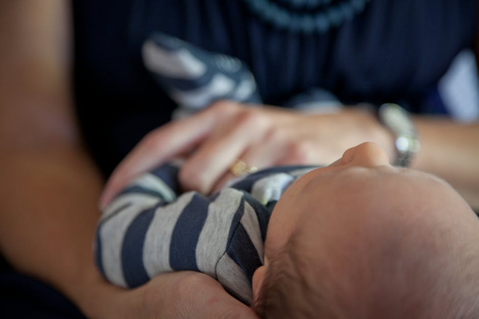 Female in Blue Top Holding Baby in Blue and Gray Stripe Top