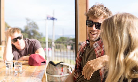 Three friends relaxing at an outdoor cafe in Australia, enjoying leisure time together.