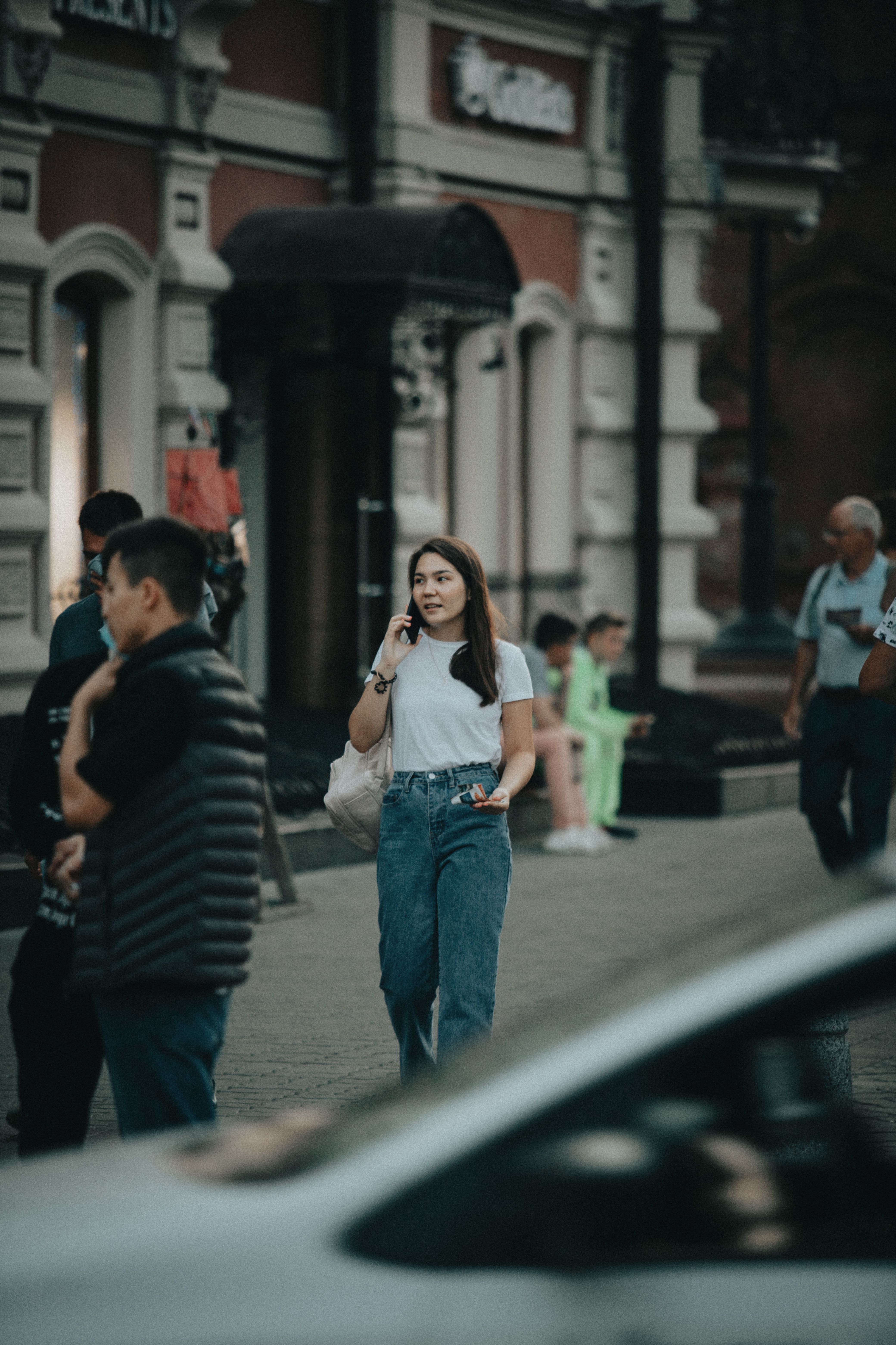 A Woman in White Shirt and Blue Denim Jeans Walking on the Street ...