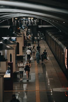 Commuters walking on an underground train station platform with a train in view.