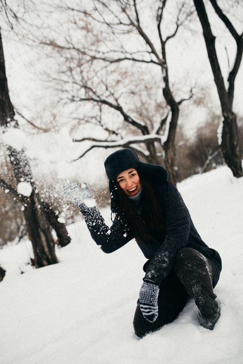 Free Woman in warm clothing having fun in a snowy forest during winter. Stock Photo