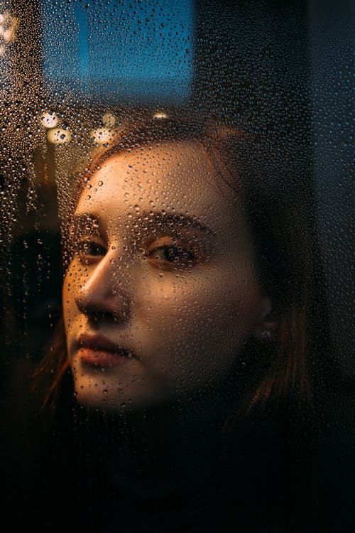 Woman Looking Through Window with Raindrops