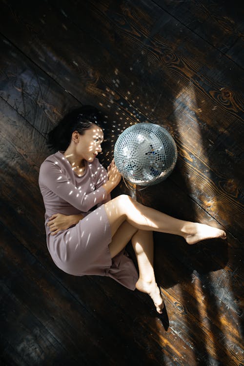 Woman Curled Up on Floor with Disco Ball