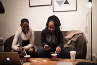 两位女士在舒适的办公室里，一边喝咖啡一边随意地聊着天