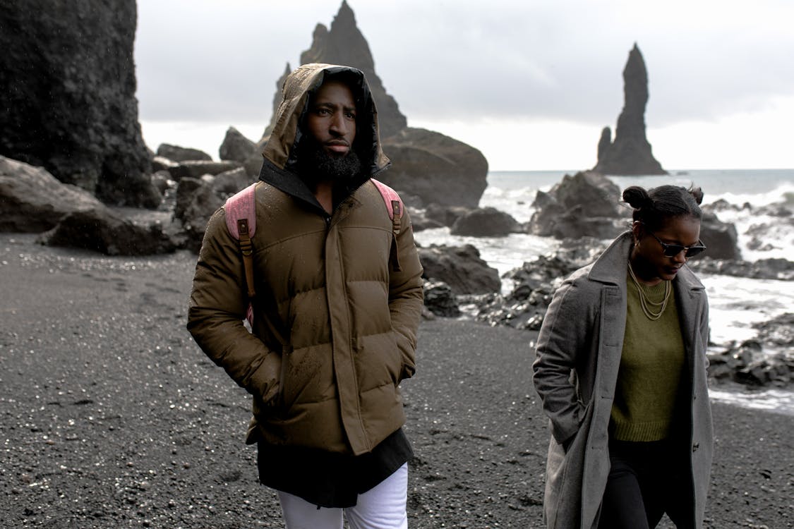 海岸を歩くジャケットを着た男と女