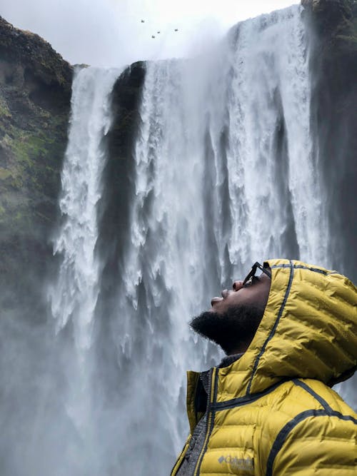 Photography of Man Wearing Bubble Hoodie Jacket Near Waterfalls