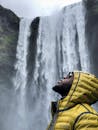 一名身穿黄色夹克的男子，正在欣赏冬日里气势磅礴的瀑布