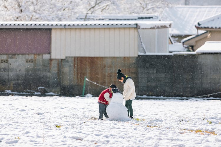 Children Building Snowman In Snow