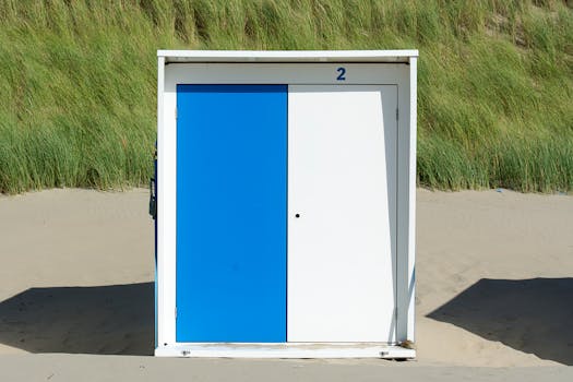 A blue and white beach hut door with number two, set against sandy dunes and grass.