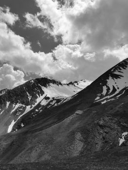 Black and white photo of Allos mountains, showcasing dramatic snow-capped peaks and clouds.
