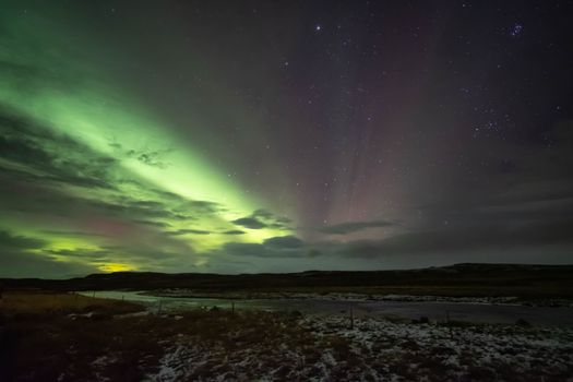 Stunning view of the Northern Lights illuminating the night sky in Iceland over a serene river.
