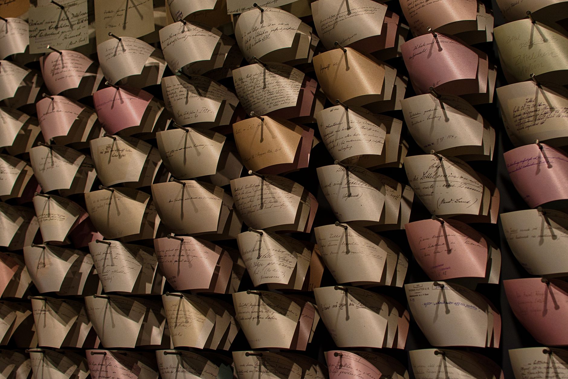 Close-up of a wall filled with organized vintage letters in a pattern, showcasing handwritten notes.