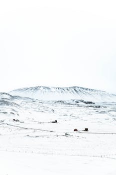 A breathtaking snow-covered Icelandic landscape with distant mountains under a bright winter sky.