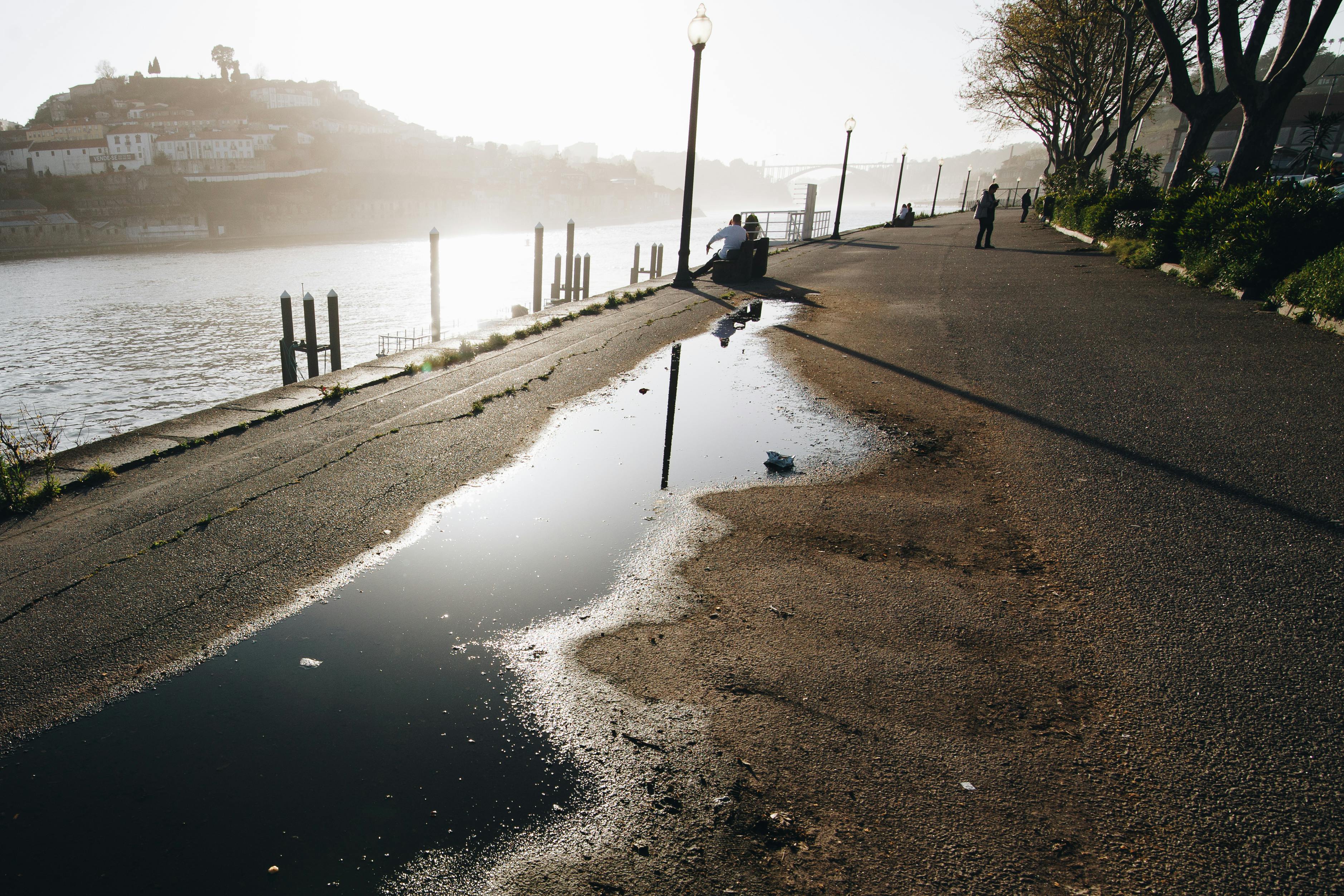 在葡萄牙波尔图，宁静的河畔小路映照着日落与水坑的倒影