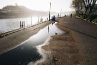 在葡萄牙波尔图，宁静的河畔小路映照着日落与水坑的倒影