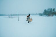 Woman Running Through Snow while Holding Packages