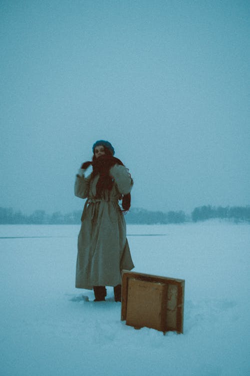 
A Woman Wearing a Coat and a Scarf on a Snow Covered Field