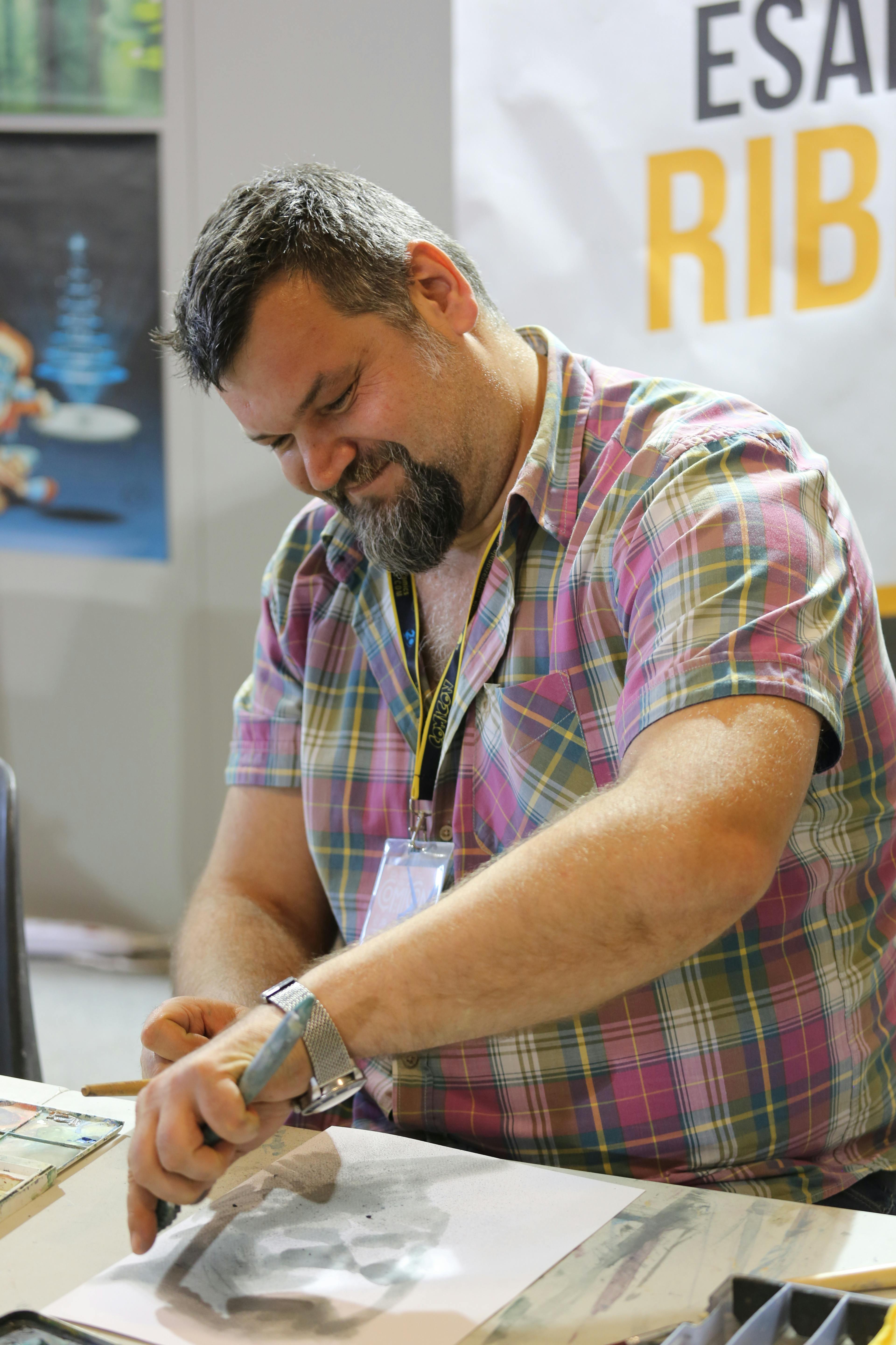 man wearing pink checkered shirt while sketching