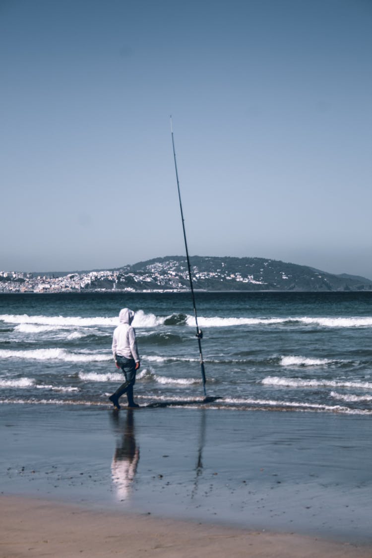 A Fisherman Surf Casting At The Beach