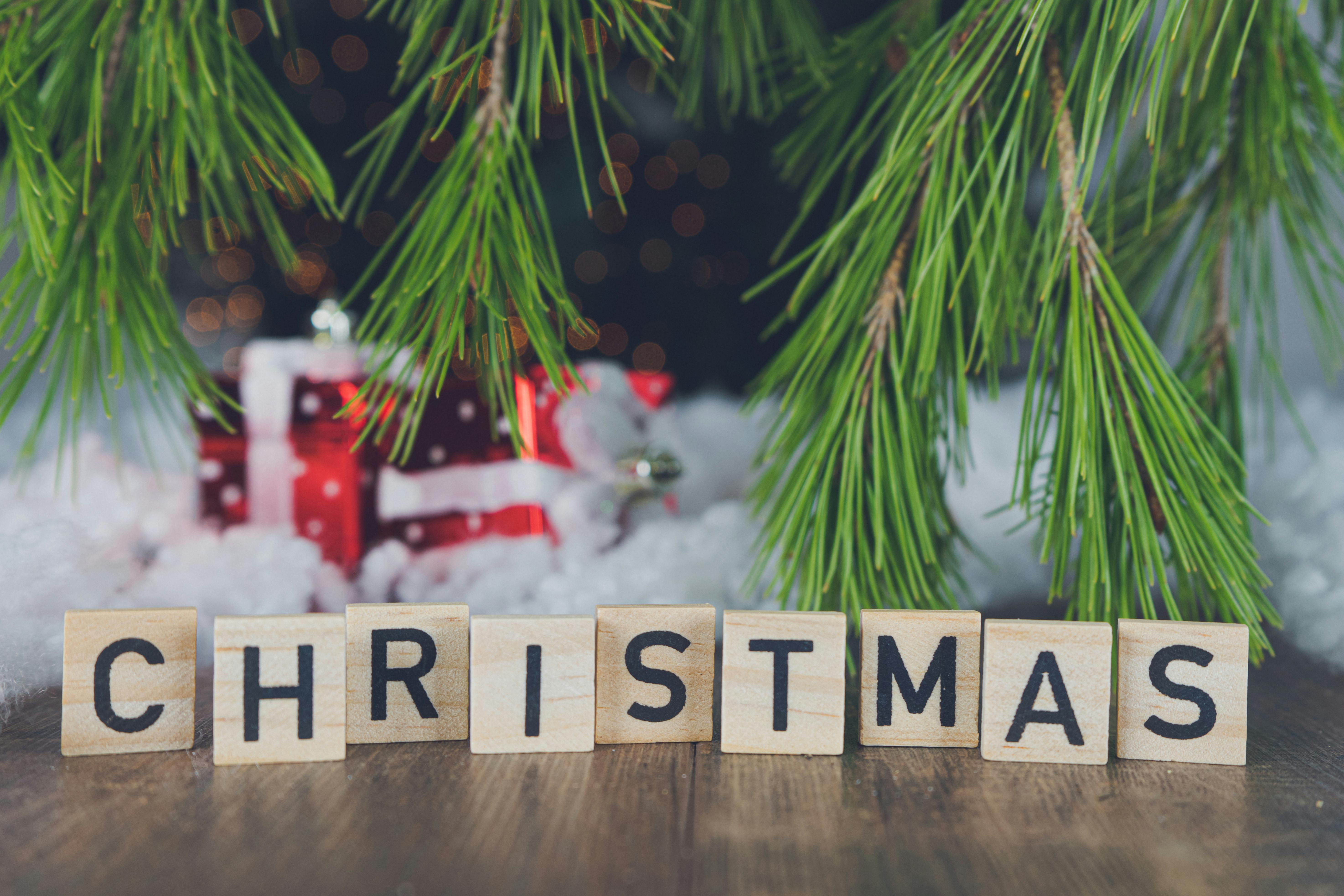 Free A festive Christmas setting featuring letter tiles spelling 'Christmas' amidst pine branches and gifts. Stock Photo
