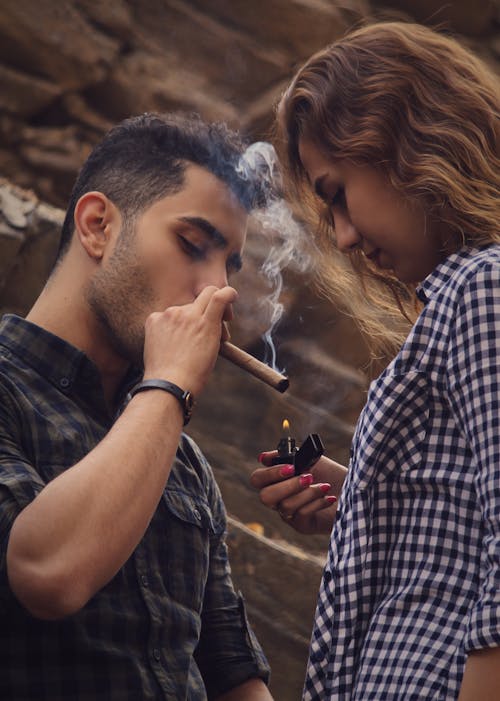 
A Woman Lighting the Cigar of a Man with a Lighted