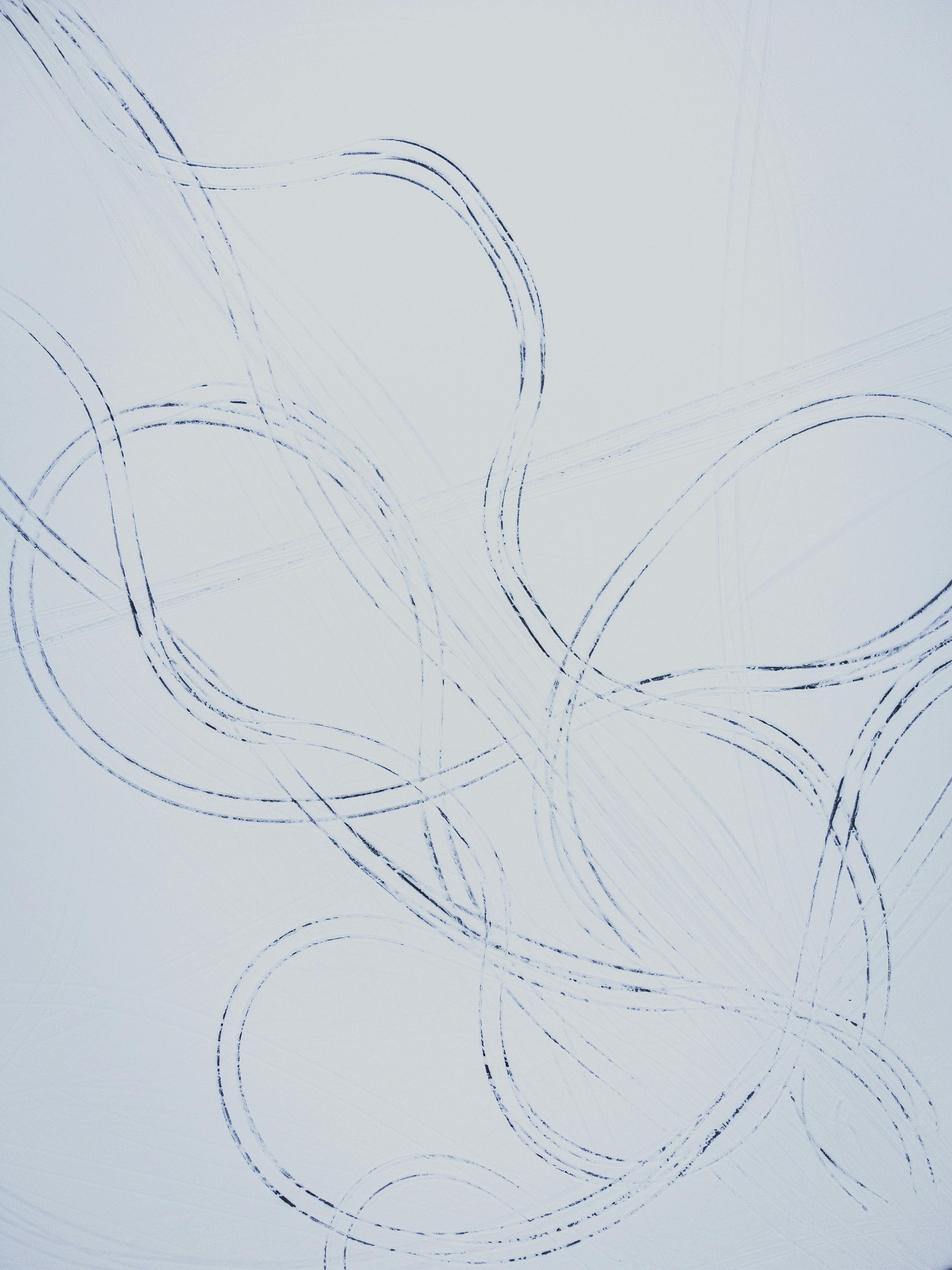 Artistic abstract pattern created by car tracks in the snow, showing intricate loops and curves.